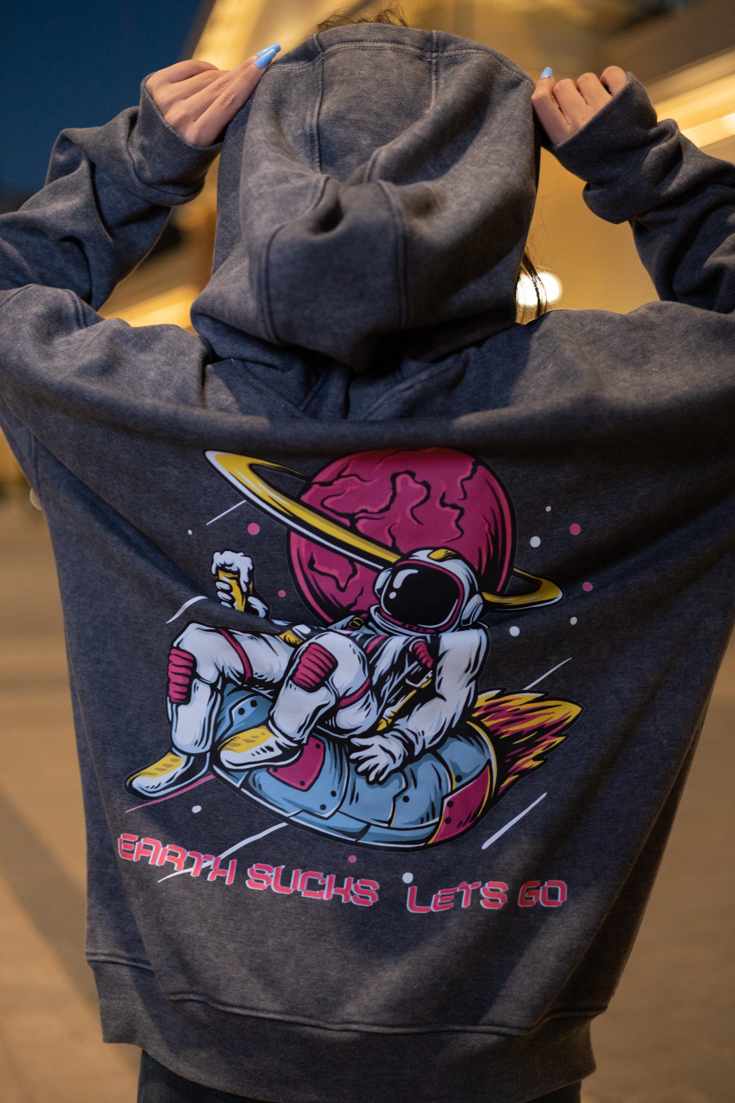 Washed grey oversized hoodie envisioning adventure with vibrant astronaut graphics floating from Earth paired with "HIGH HERE" Mars type for interstellar dreams.