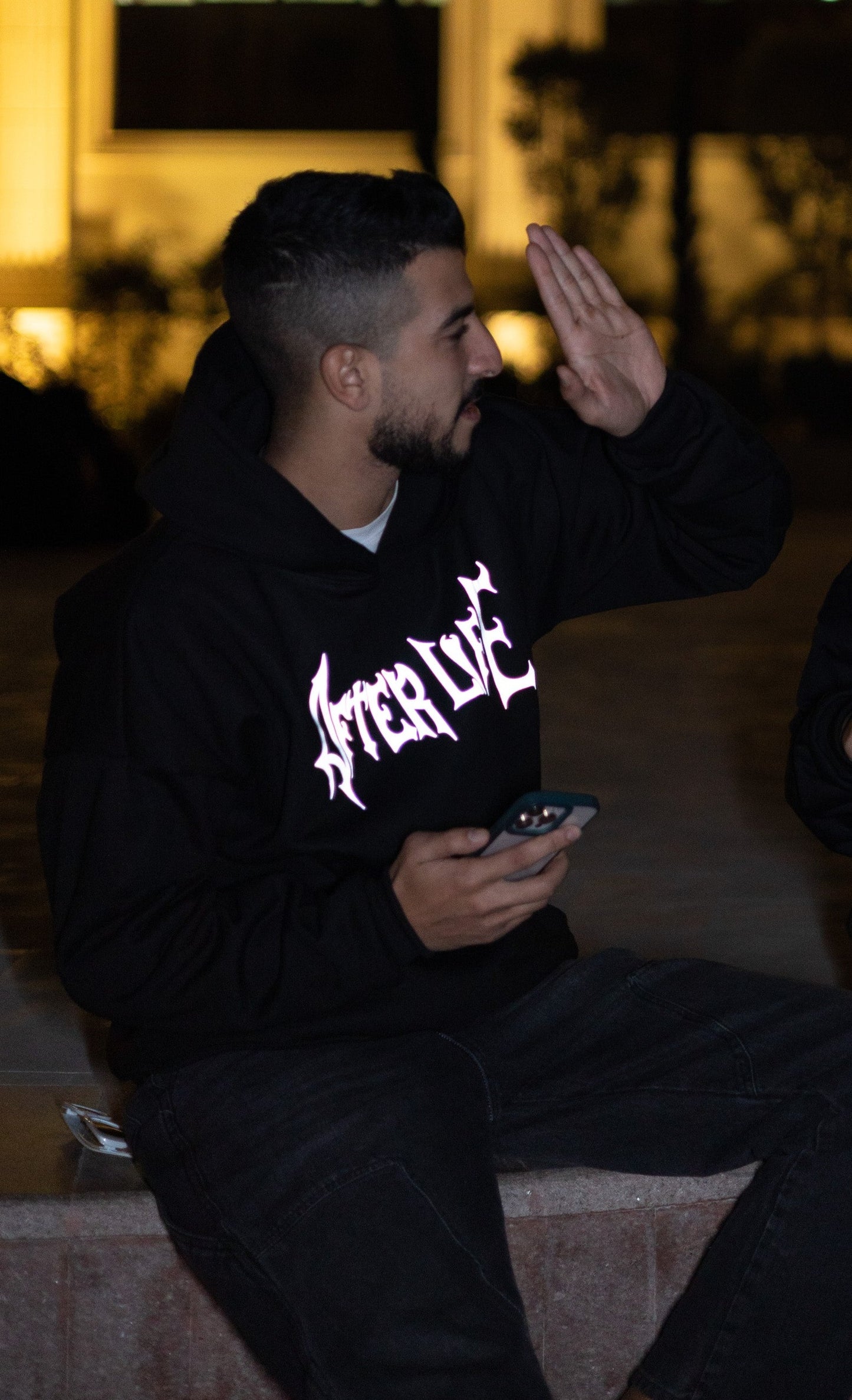 Edgy black oversized hoodie with glowing reflective "After Life" text and logo graphic when hit by light - made for making a scene at night festivals.